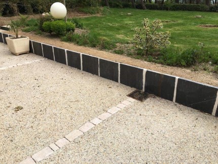 Aménagement paysager d'une terrasse en béton désactivé avec pavés et palis de schiste
